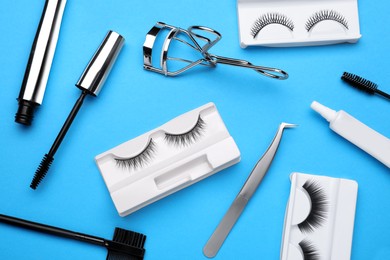 Flat lay composition with fake eyelashes, brushes and tools on light blue background