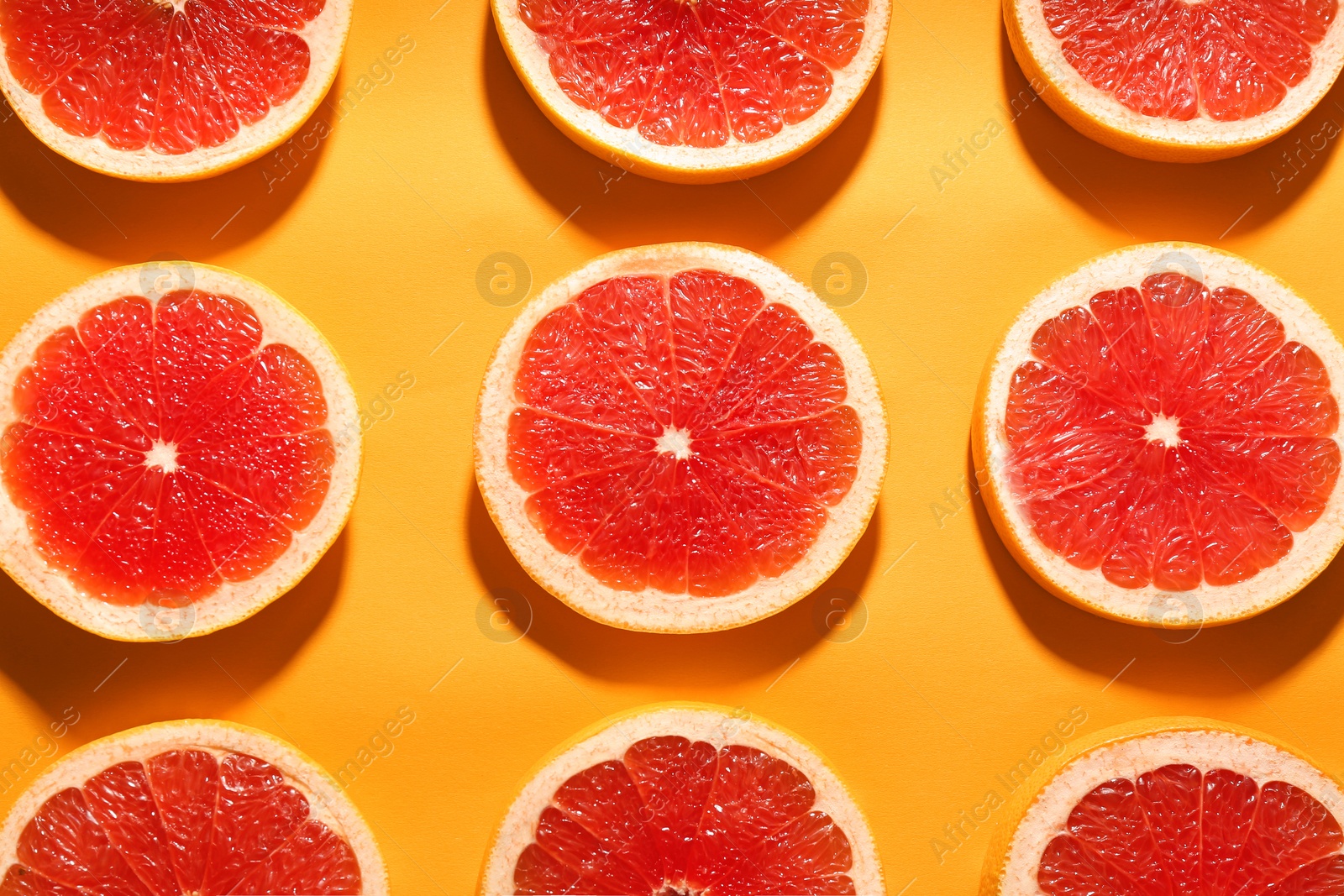 Photo of Flat lay composition with tasty ripe grapefruit slices on orange background