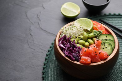 Photo of Delicious poke bowl with vegetables, fish and edamame beans on black table, space for text