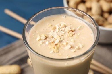 Photo of Glass of tasty banana smoothie with peanuts, closeup