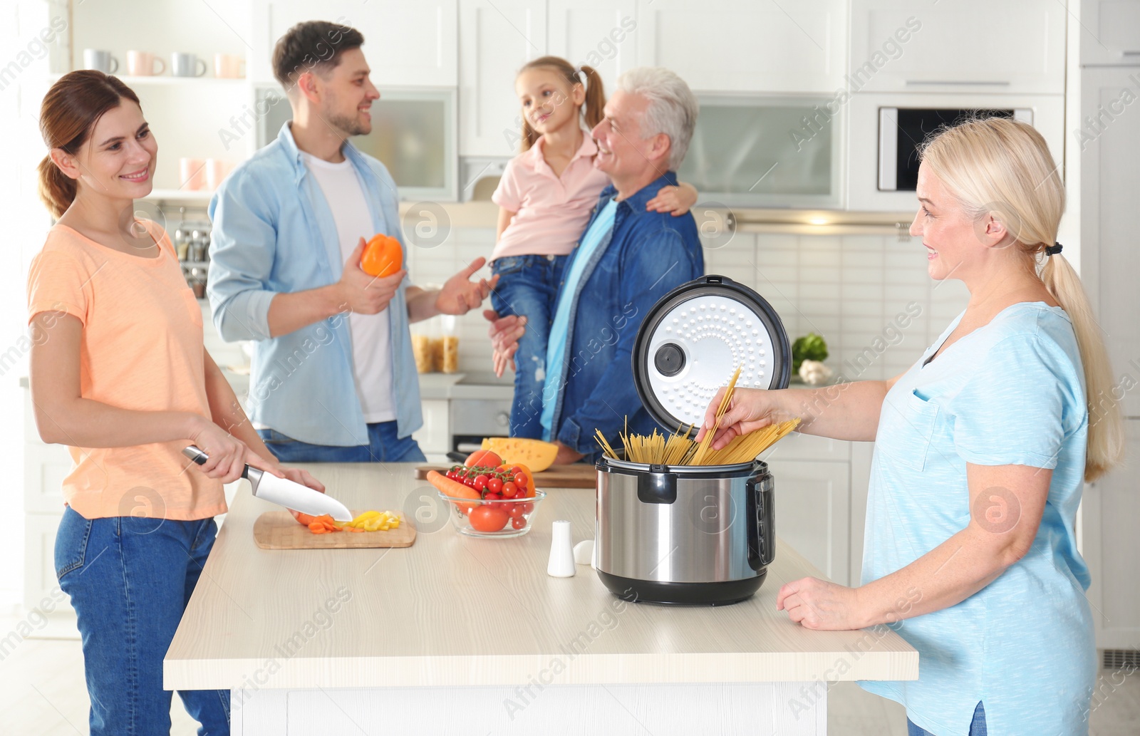 Photo of Happy family preparing food with modern multi cooker in kitchen