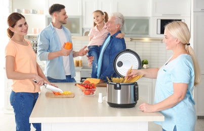 Happy family preparing food with modern multi cooker in kitchen