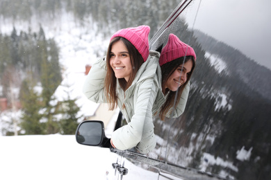 Photo of Happy young woman looking out of car window on road. Winter vacation
