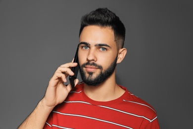 Photo of Portrait of handsome young man with mobile phone on gray background