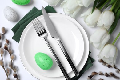 Photo of Festive table setting with tulips and willow twigs on white background, above view. Easter celebration