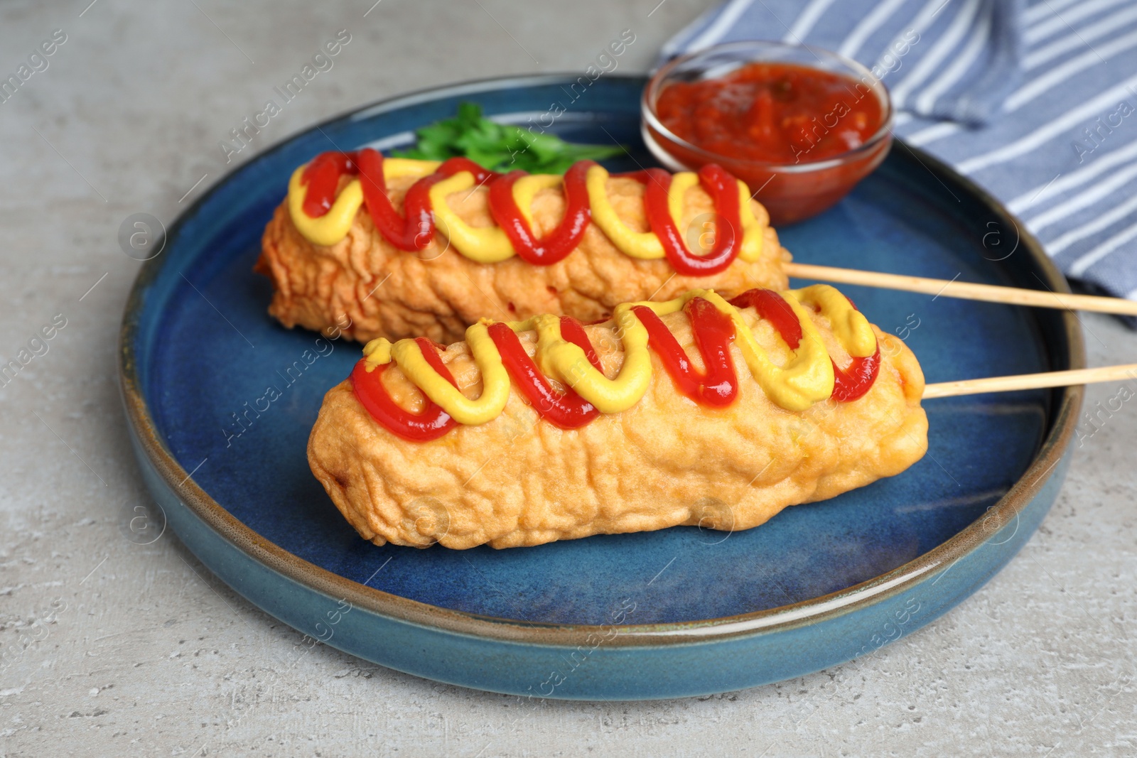 Photo of Delicious corn dogs with mustard and ketchup served on light table, closeup