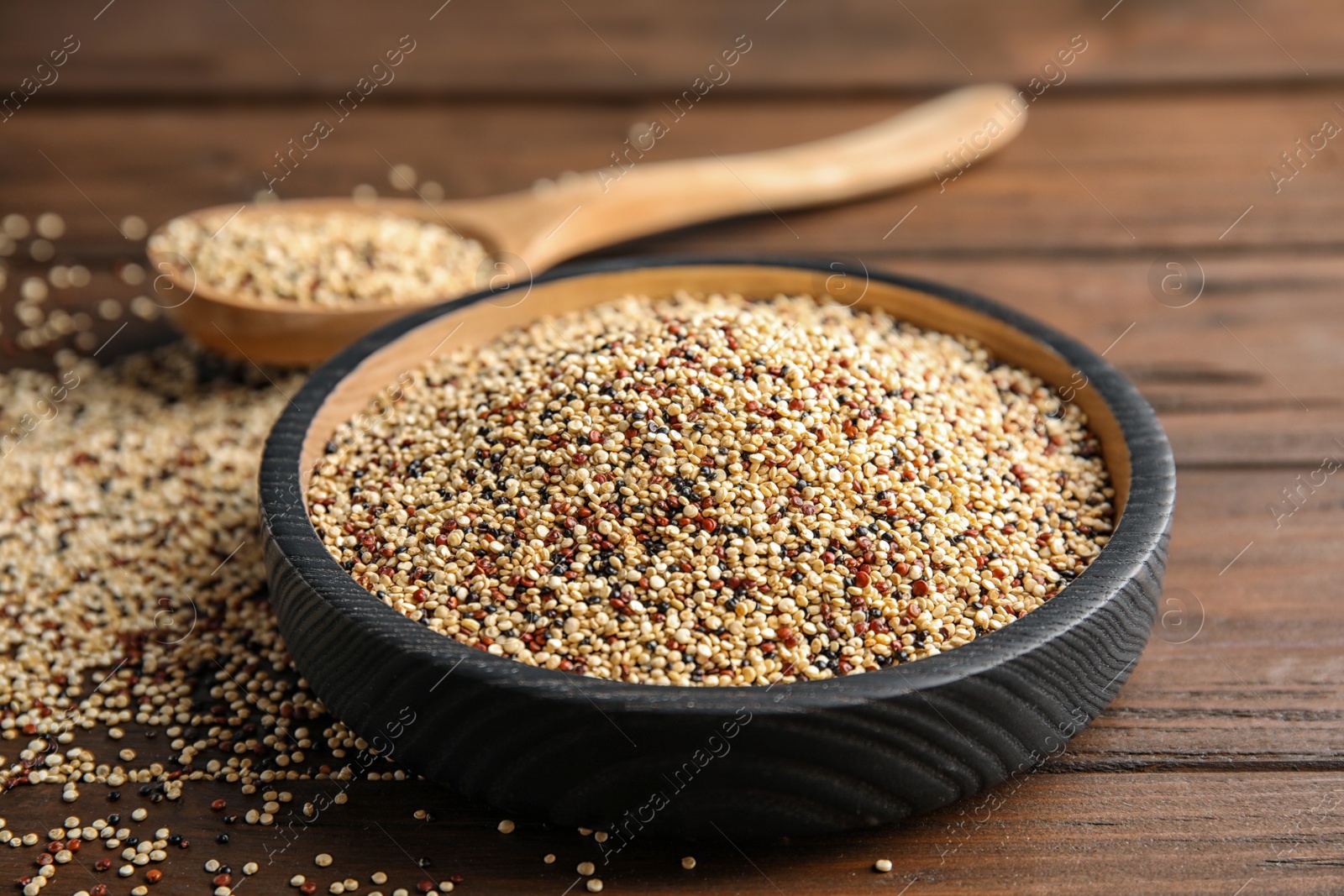 Photo of Plate with mixed quinoa seeds on wooden table