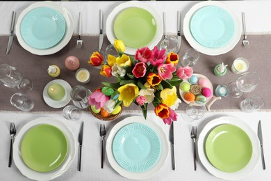 Photo of Easter celebration. Festive table setting with beautiful flowers and painted eggs, flat lay