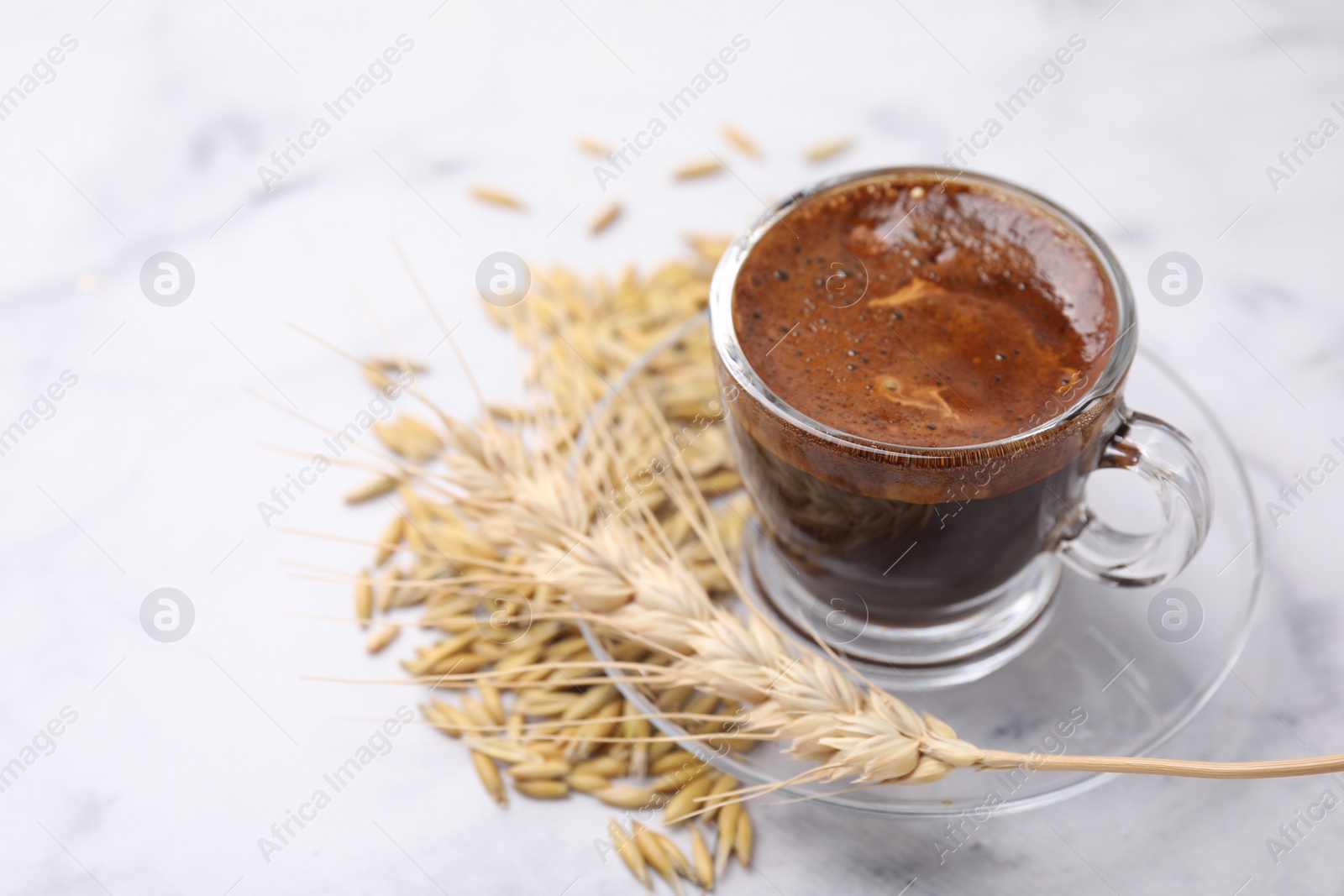 Photo of Cup of barley coffee, grains and spike on light table, closeup. Space for text