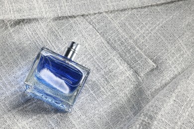 Photo of Luxury men's perfume in bottle on grey jacket, above view. Space for text