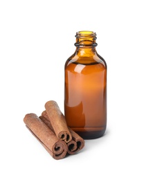 Photo of Bottle of essential oil and cinnamon sticks on white background