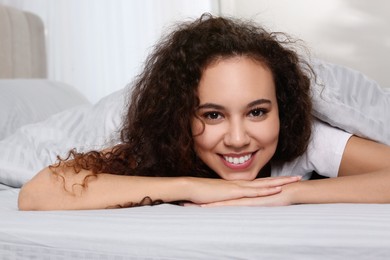 Happy beautiful African American woman lying in bed at home