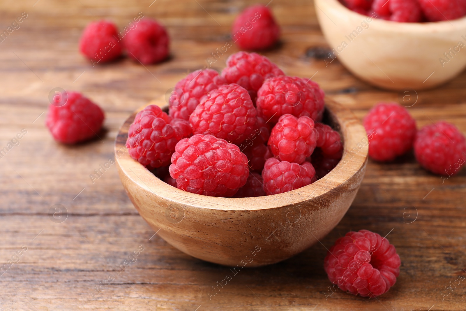 Photo of Tasty ripe raspberries in bowl on wooden table, closeup