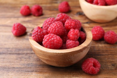 Photo of Tasty ripe raspberries in bowl on wooden table, closeup
