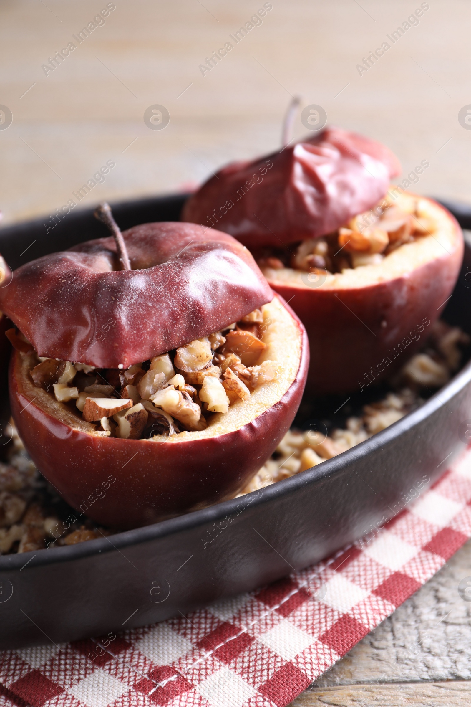 Photo of Tasty baked apples with nuts in baking dish on table, closeup