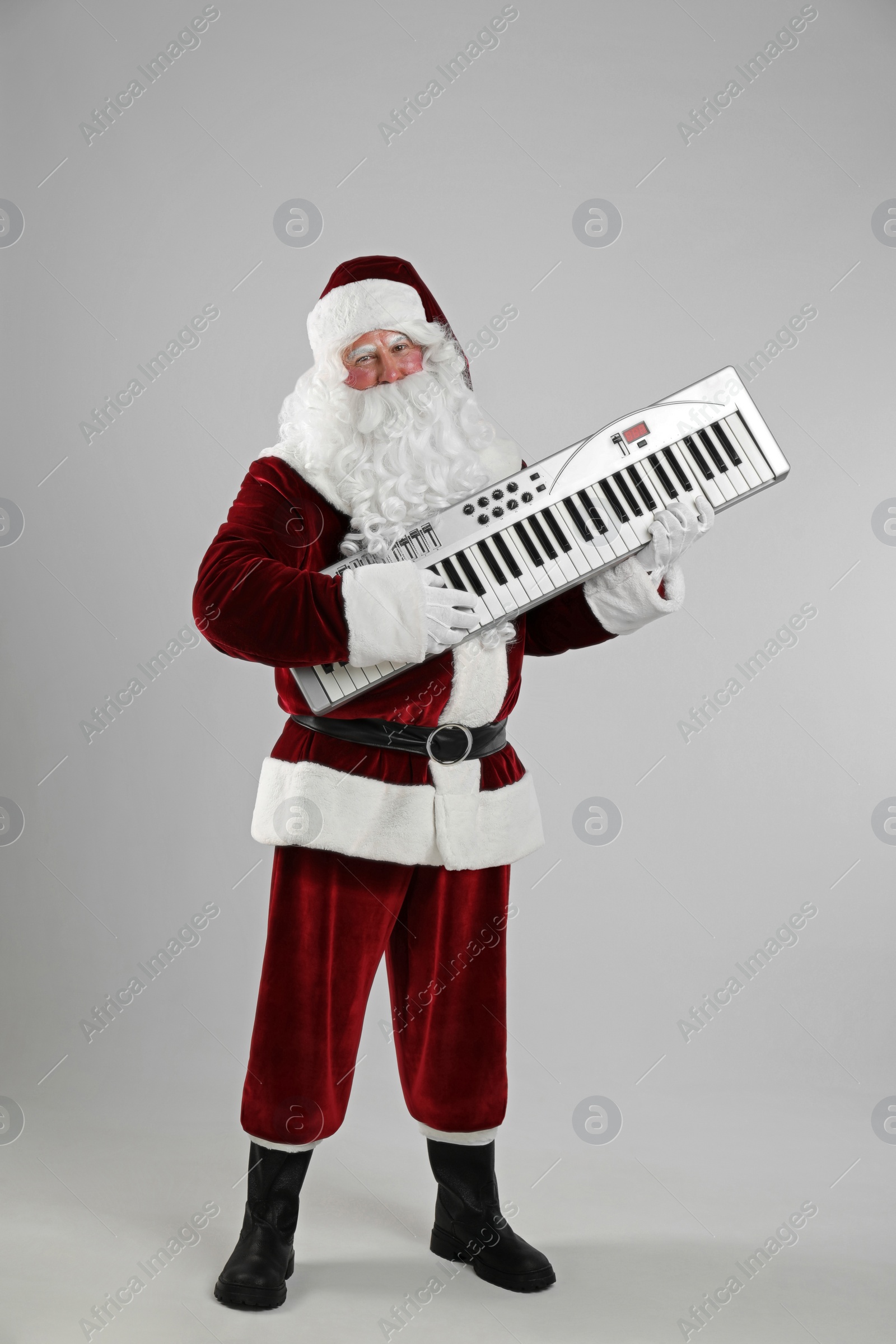 Photo of Santa Claus with synthesizer on light grey background. Christmas music