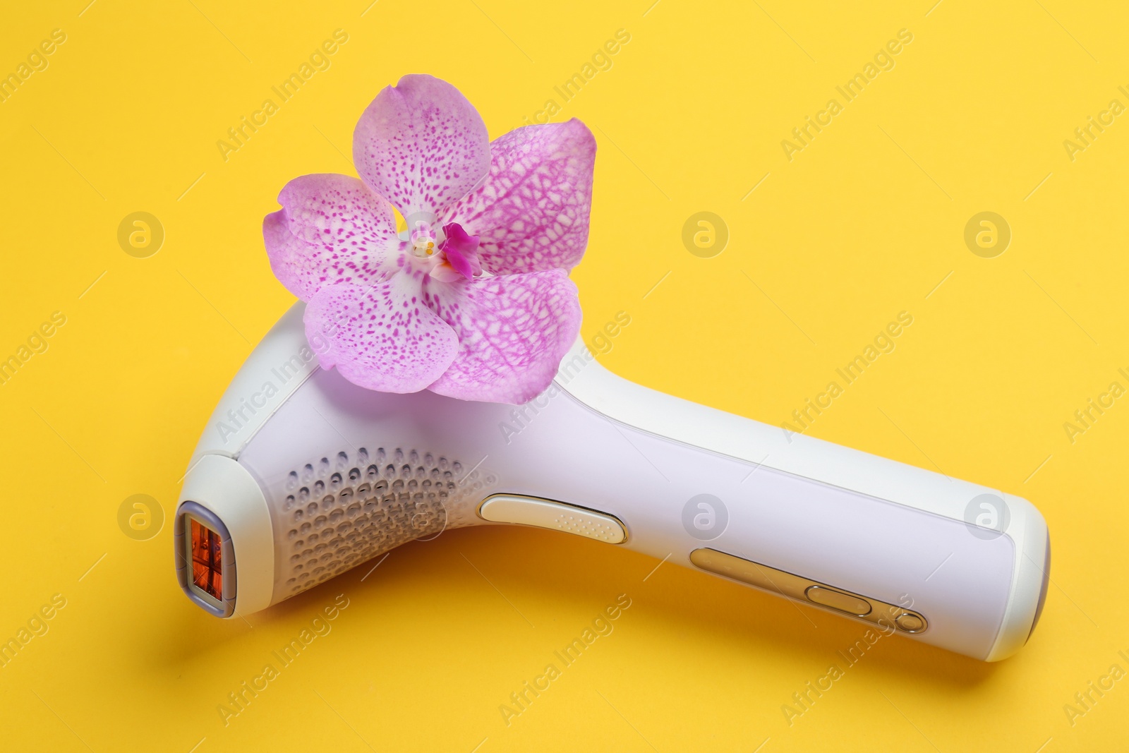 Image of Modern photoepilator with orchid flower on yellow background 