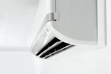 Photo of Modern air conditioner on white wall indoors, closeup. Space for text