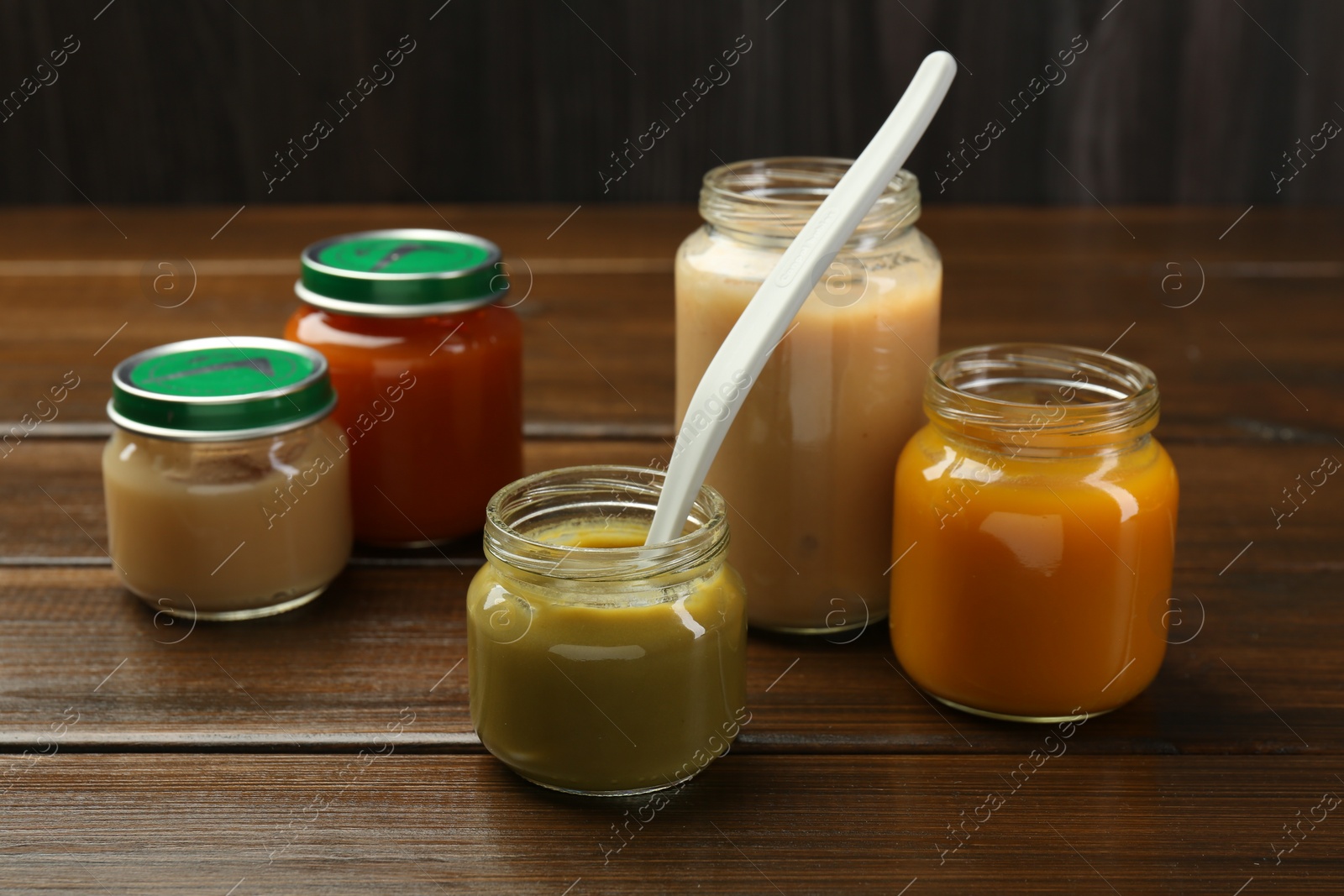 Photo of Tasty baby food in jars on wooden table