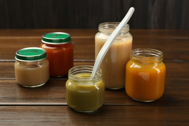 Tasty baby food in jars on wooden table