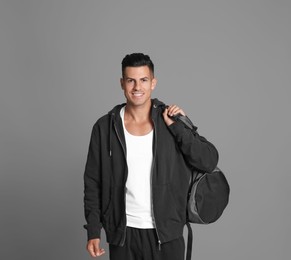 Photo of Handsome man with sports bag on grey background