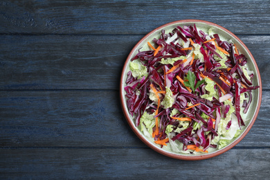 Photo of Fresh cabbage salad served on blue wooden table, top view. Space for text