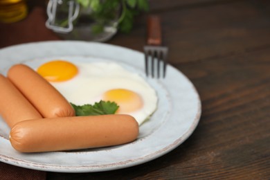 Photo of Delicious boiled sausages, fried eggs and parsley on wooden table, closeup