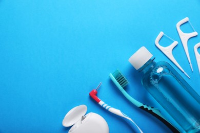 Dental floss and different teeth care products on light blue background, flat lay. Space for text