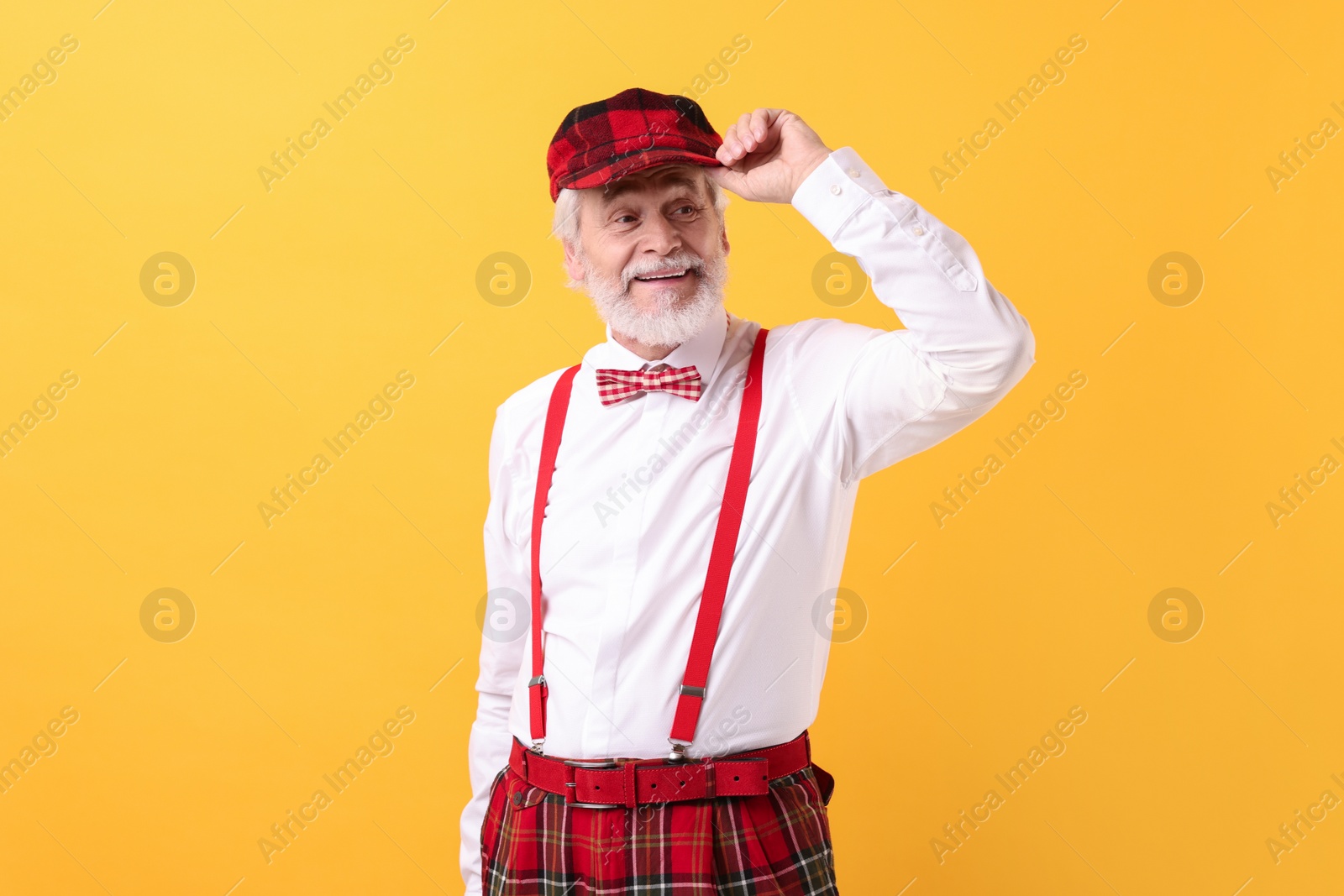 Photo of Portrait of grandpa with stylish hat and bowtie on yellow background