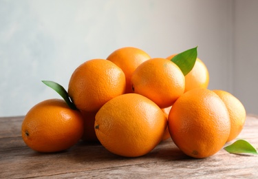 Fresh oranges with leaves on wooden table