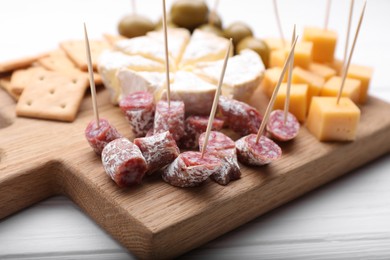 Toothpick appetizers. Pieces of sausage on wooden board, closeup