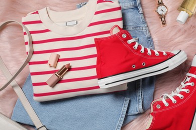 Pair of stylish red shoes, accessories and clothes on faux fur rug, flat lay