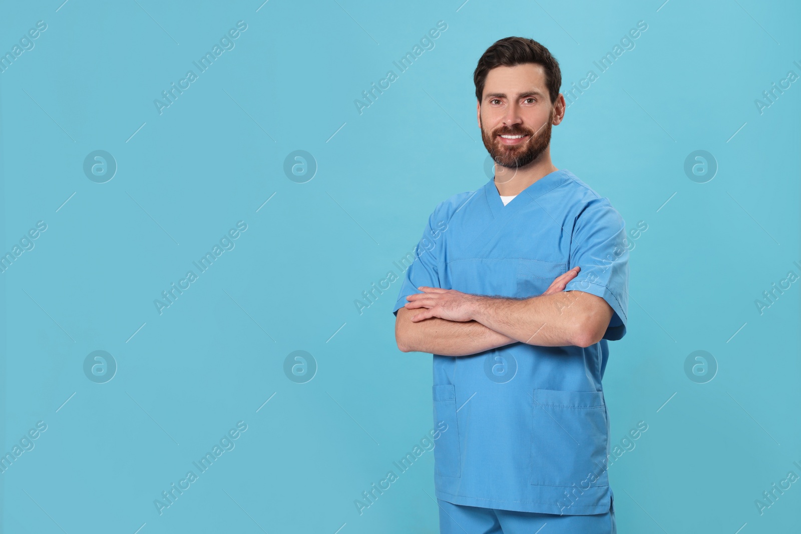 Photo of Happy nurse in medical uniform on light blue background, space for text