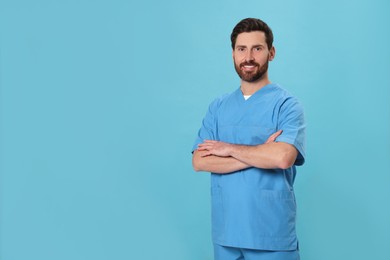 Photo of Happy nurse in medical uniform on light blue background, space for text