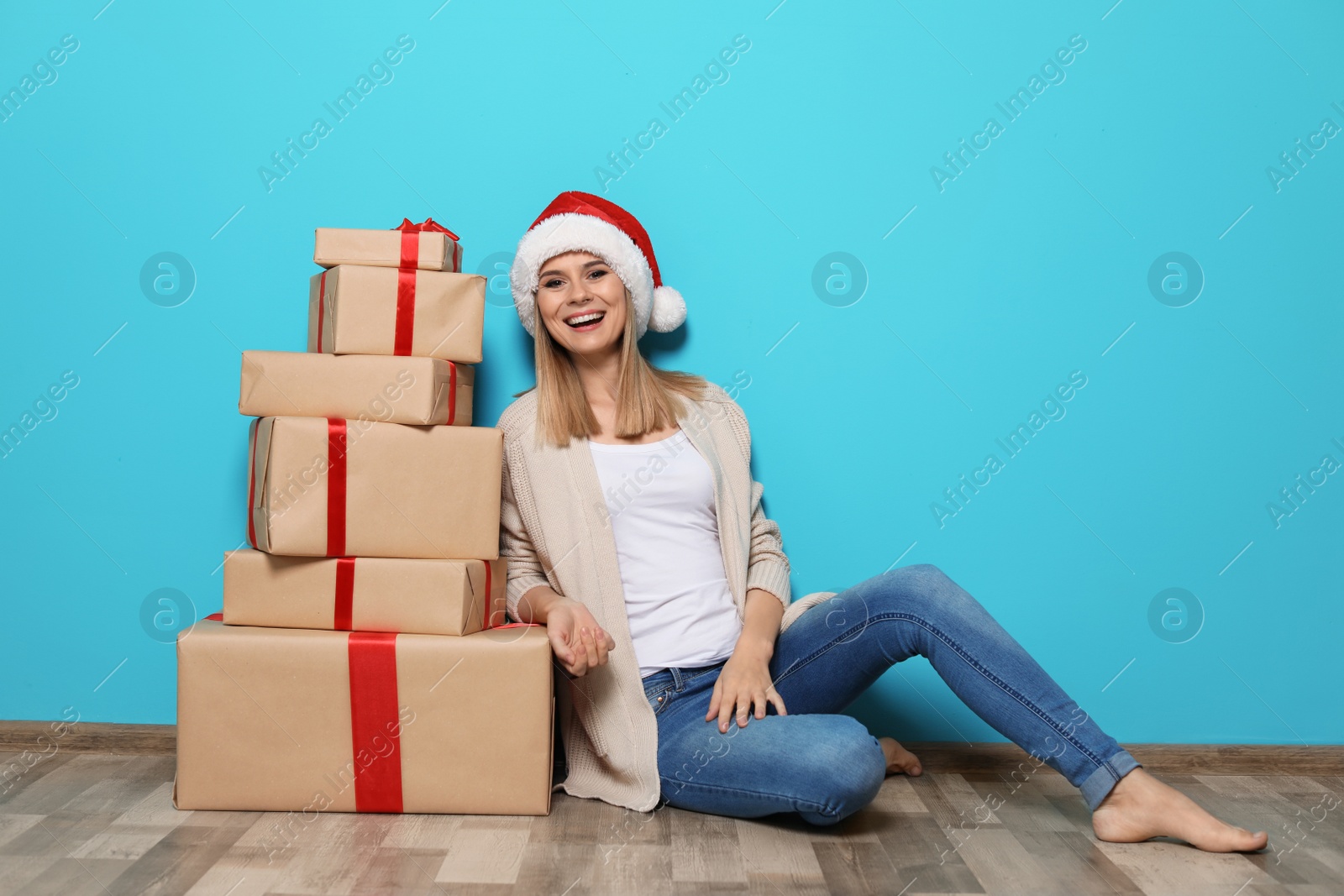 Photo of Young woman with Christmas gifts near color wall