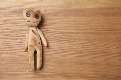 Voodoo doll pierced with pins on wooden table, top view. Space for text