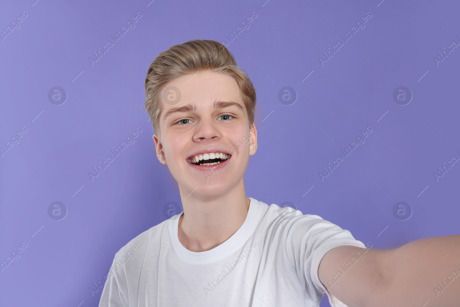 Photo of Teenage boy taking selfie on purple background