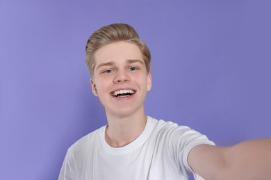Photo of Teenage boy taking selfie on purple background