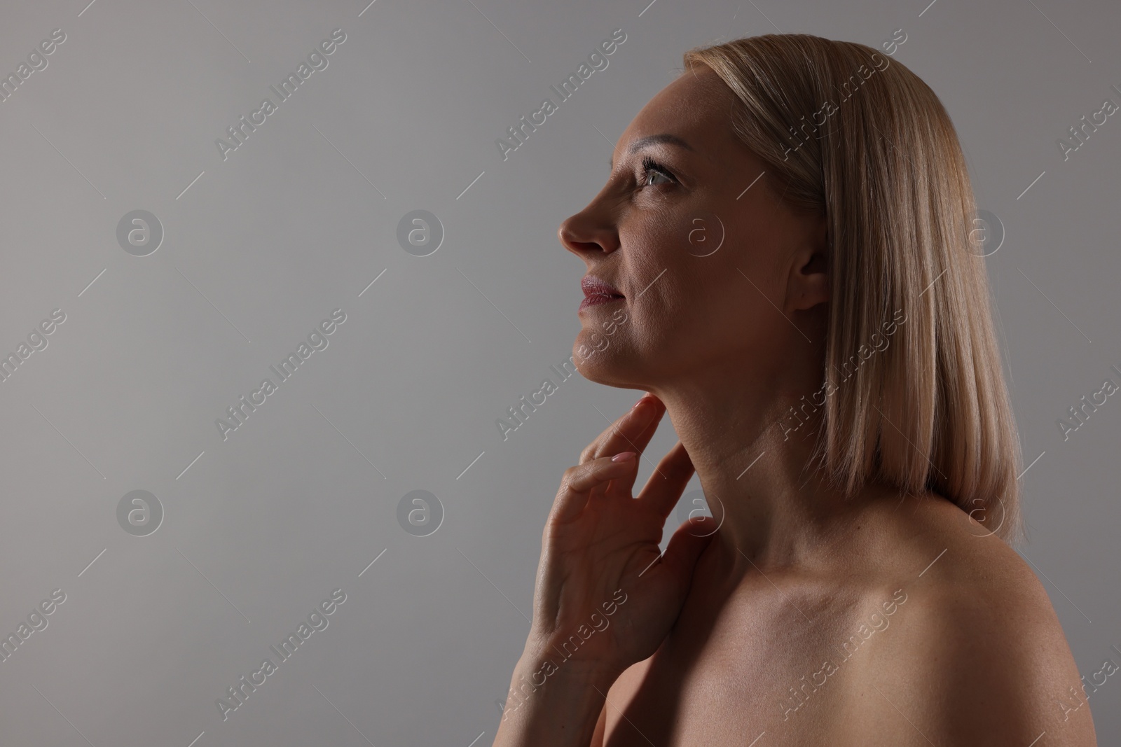 Photo of Beautiful woman touching her neck on grey background. Space for text