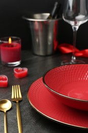 Photo of Place setting with heart shaped candles on dark gray table, closeup. Romantic dinner