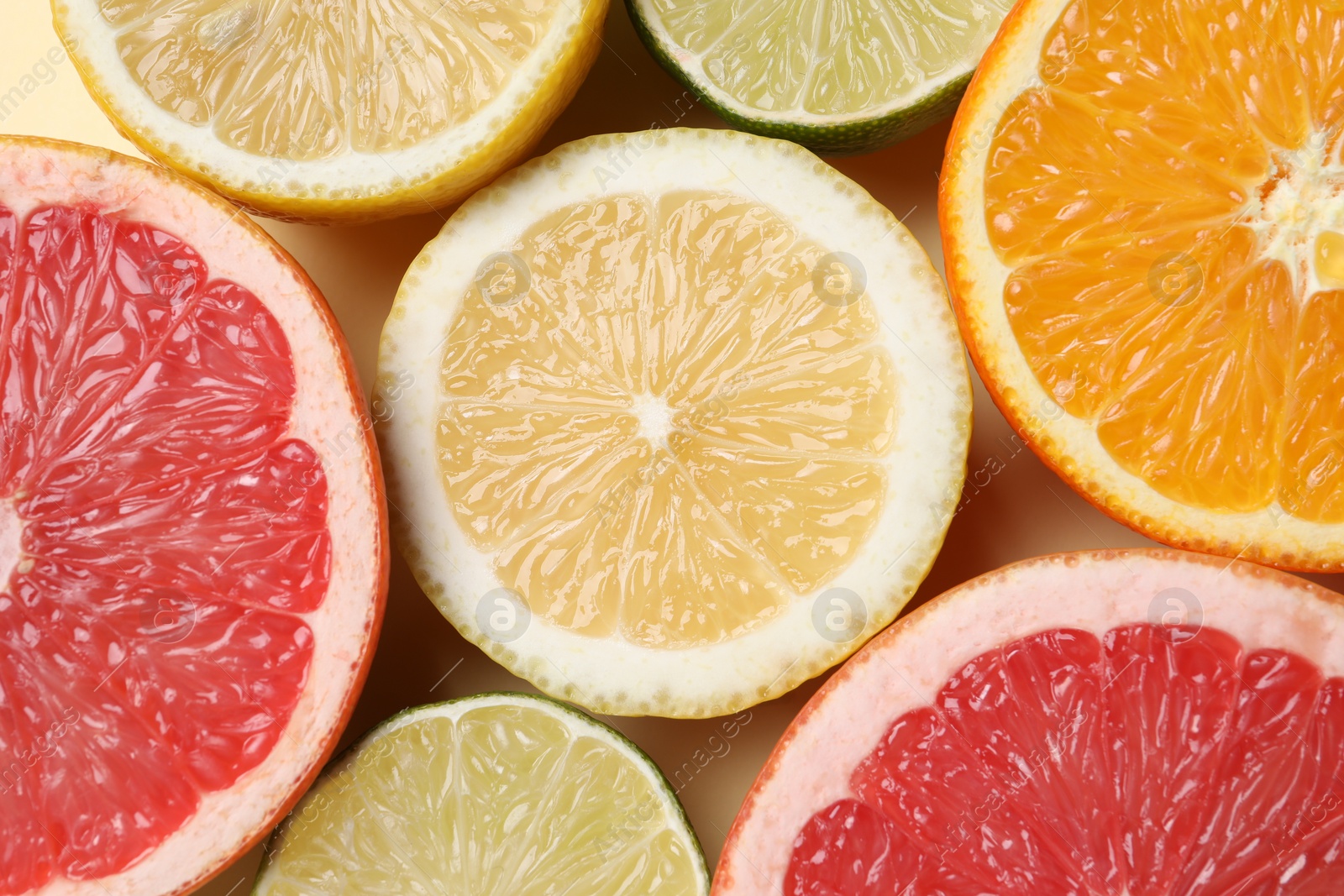 Photo of Different cut citrus fruits on beige table, flat lay