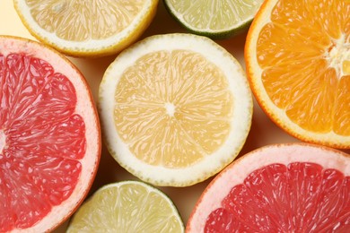 Different cut citrus fruits on beige table, flat lay