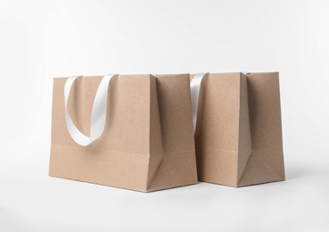 Photo of Paper shopping bags with ribbon handles on white background. Mockup for design