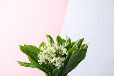 Photo of Beautiful lily of the valley flowers on color background, space for text