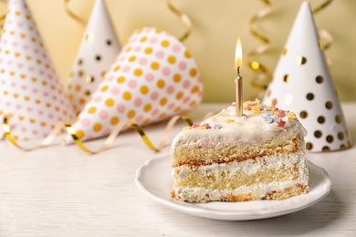 Photo of Slice of delicious birthday cake with candle on table