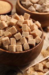 Photo of Bowl with refined sugar cubes on table, closeup