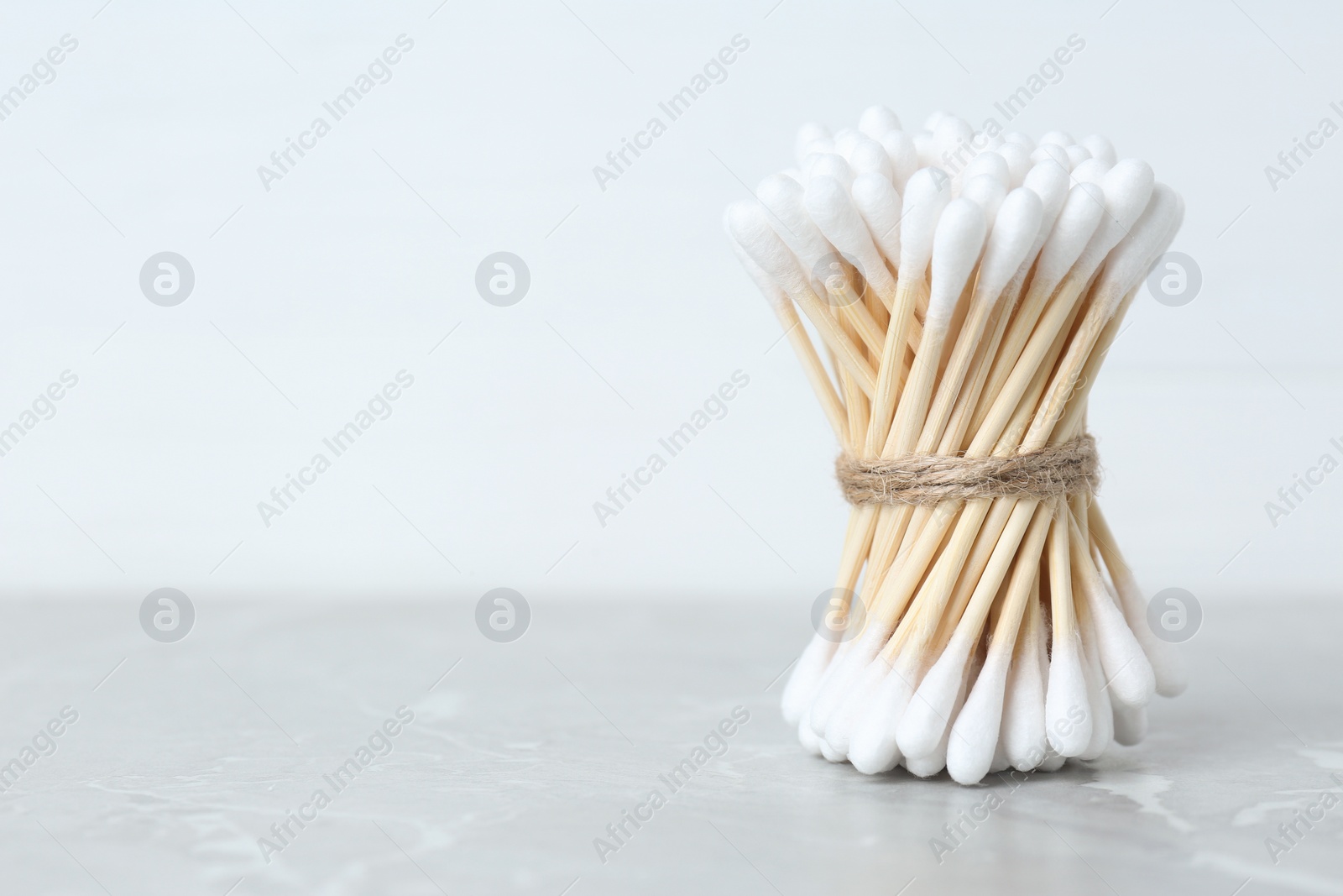 Photo of Many cotton buds on light grey marble table, space for text