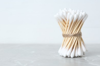 Photo of Many cotton buds on light grey marble table, space for text