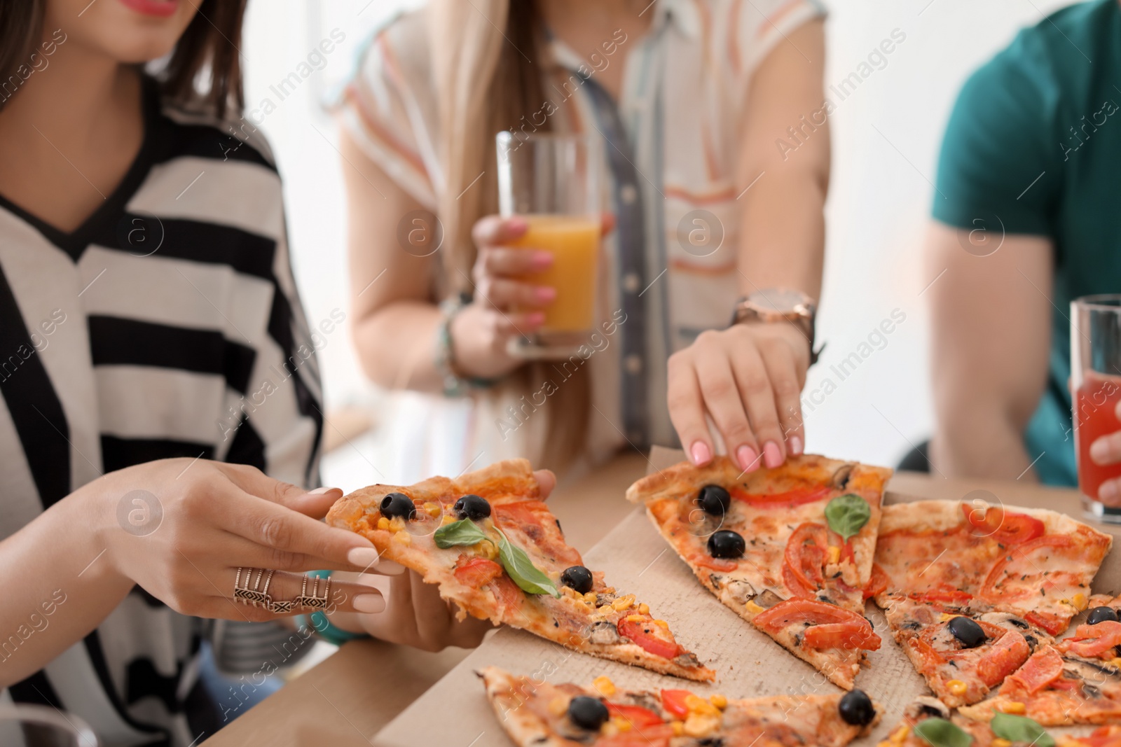 Photo of Young people eating delicious pizza at table, closeup