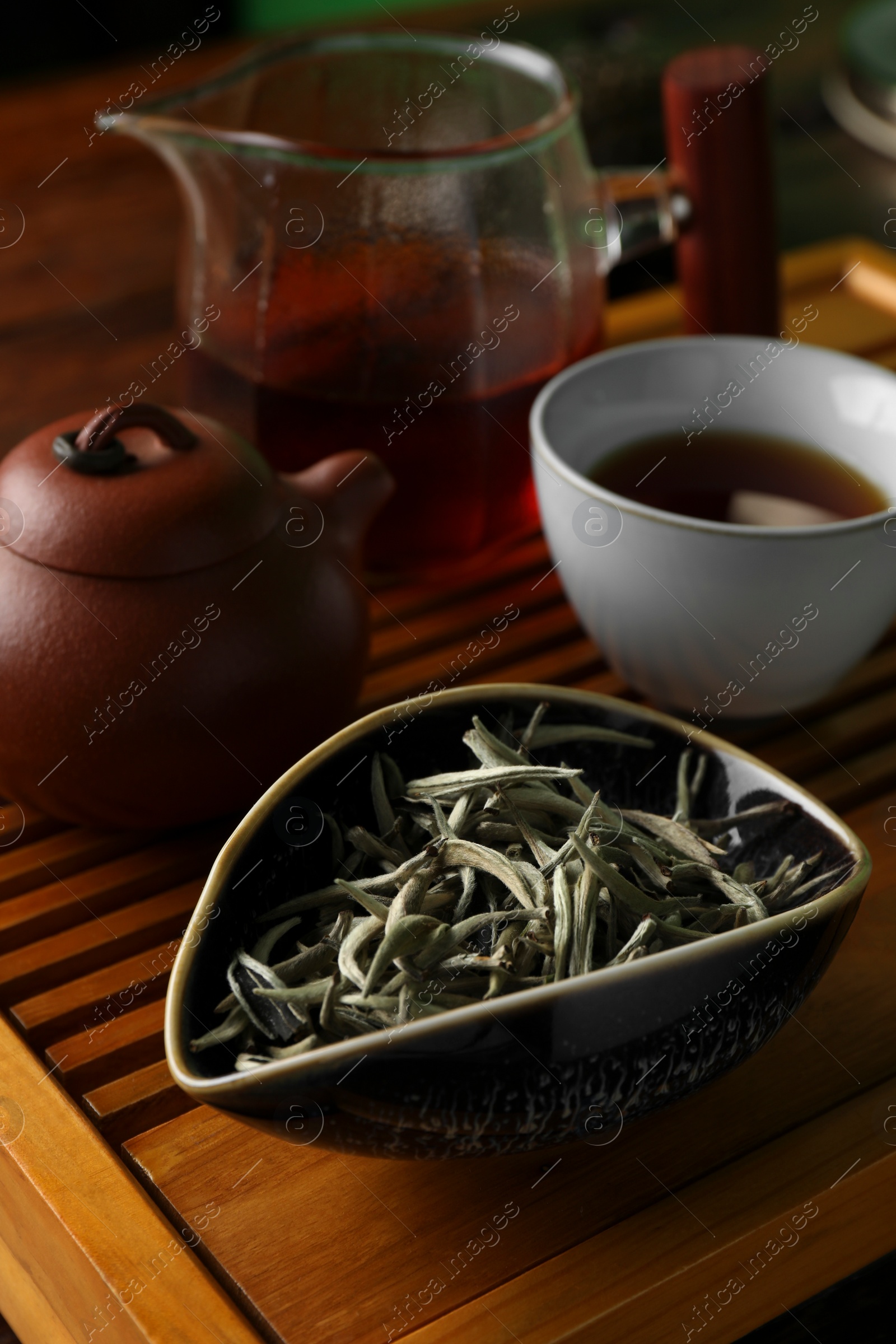 Photo of Aromatic Baihao Yinzhen tea and teapot on wooden tray, closeup. Traditional ceremony